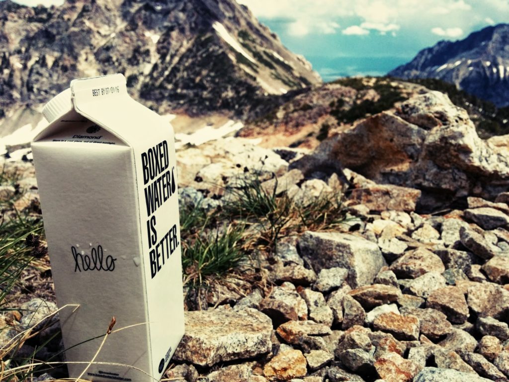 A container of Boxed Water on a rocky hill