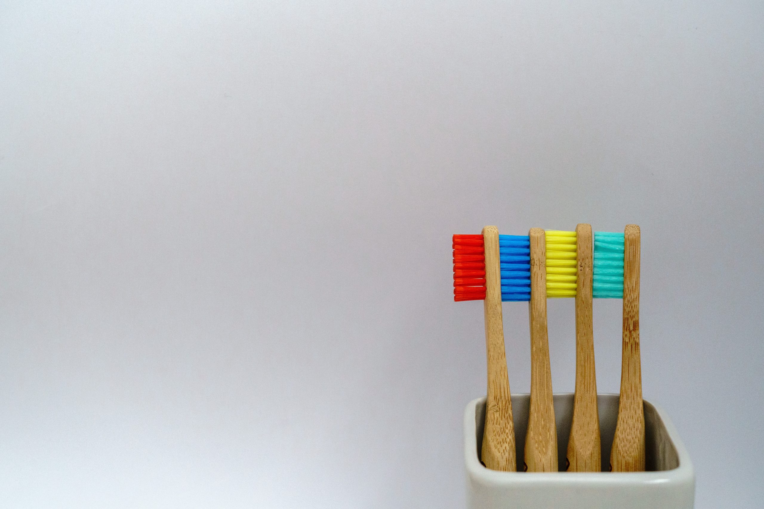Wooden handle toothbrushes with bristles of various colors: red, blue, yellow, and green