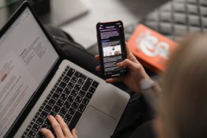 A person using a mobile phone and a laptop simultaneously