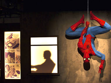 Spider-Man hangs upside down giving the peace sign in this Marvel exhibit